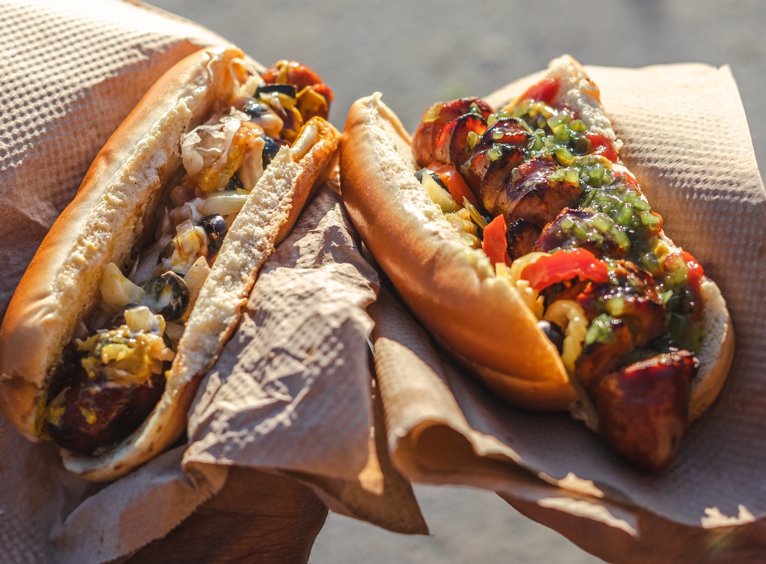 Two Sun Dogs Eatery gourmet hot dogs held up in paper wrapping